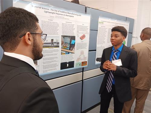 Student speaking with gentleman in front of a presentation